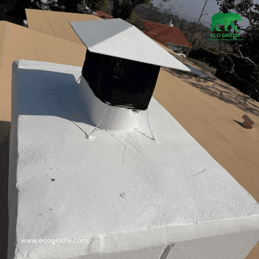 White chimney crown with silver and black chimney cap installed on a tan roof