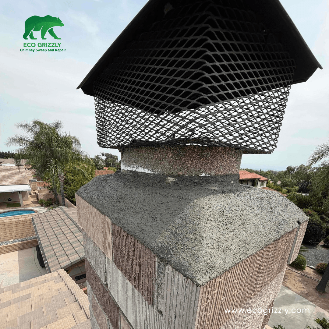 Stone facade chimney with freshly repaired concrete crown and black metal mesh cap