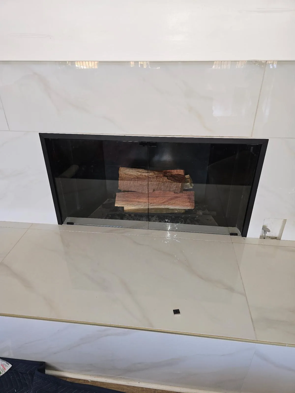 Fireplace glass door installation in progress on a masonry firebox in Southern California