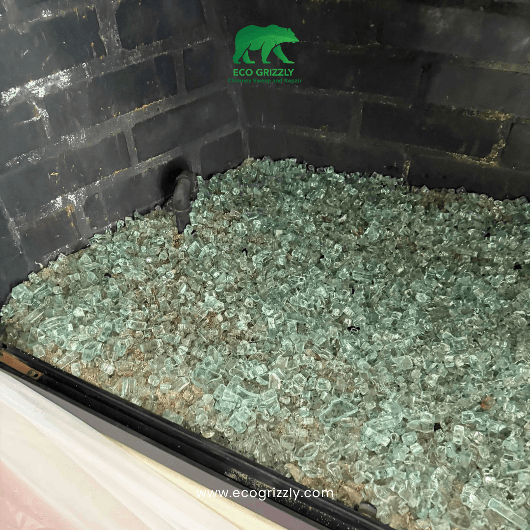 Fireplace filled with glass media and black brick walls during media replacement