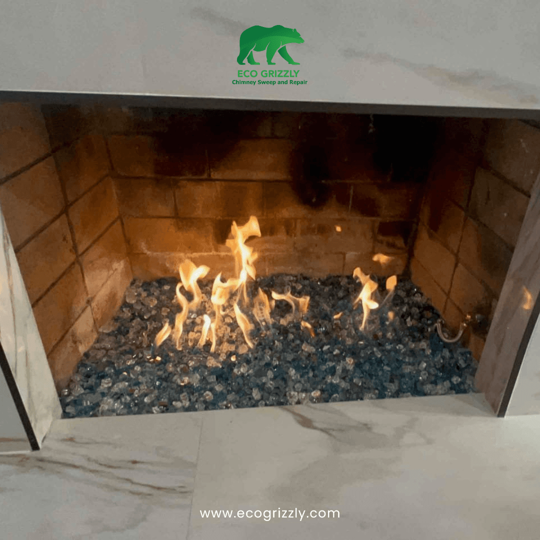 Modern fireplace with marble surround and glass fire media burning with orange flames