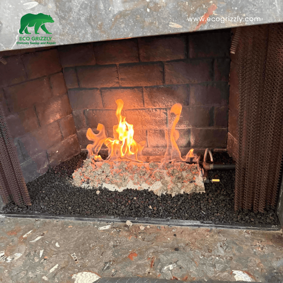 Gas fireplace with realistic logs burning in a dark brick firebox with metal mesh screens