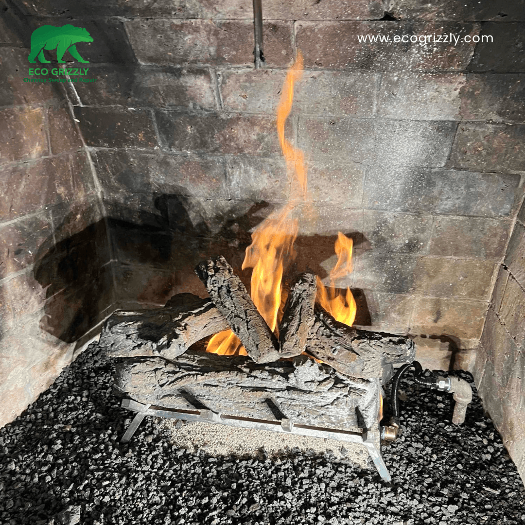 Gas fireplace with artificial logs burning in a brick firebox over a bed of dark gravel