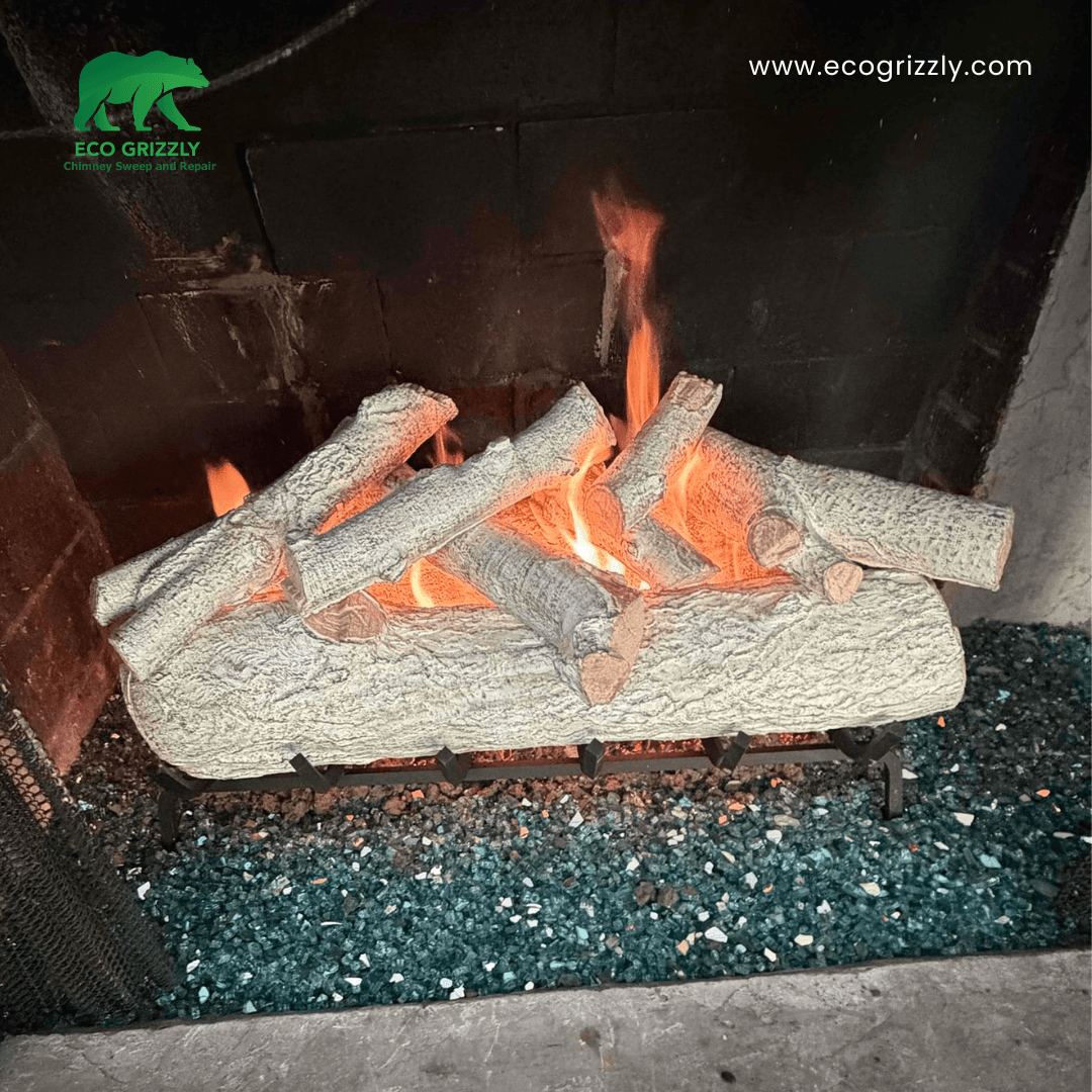 Gas log set burning on a grate over blue glass embers inside a brick fireplace