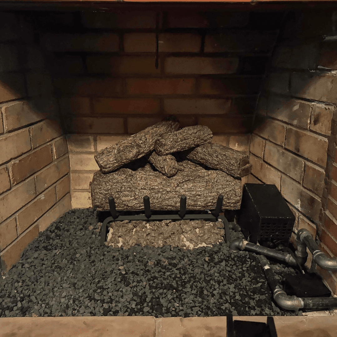 Gas log set with ember bed burning in a residential brick fireplace