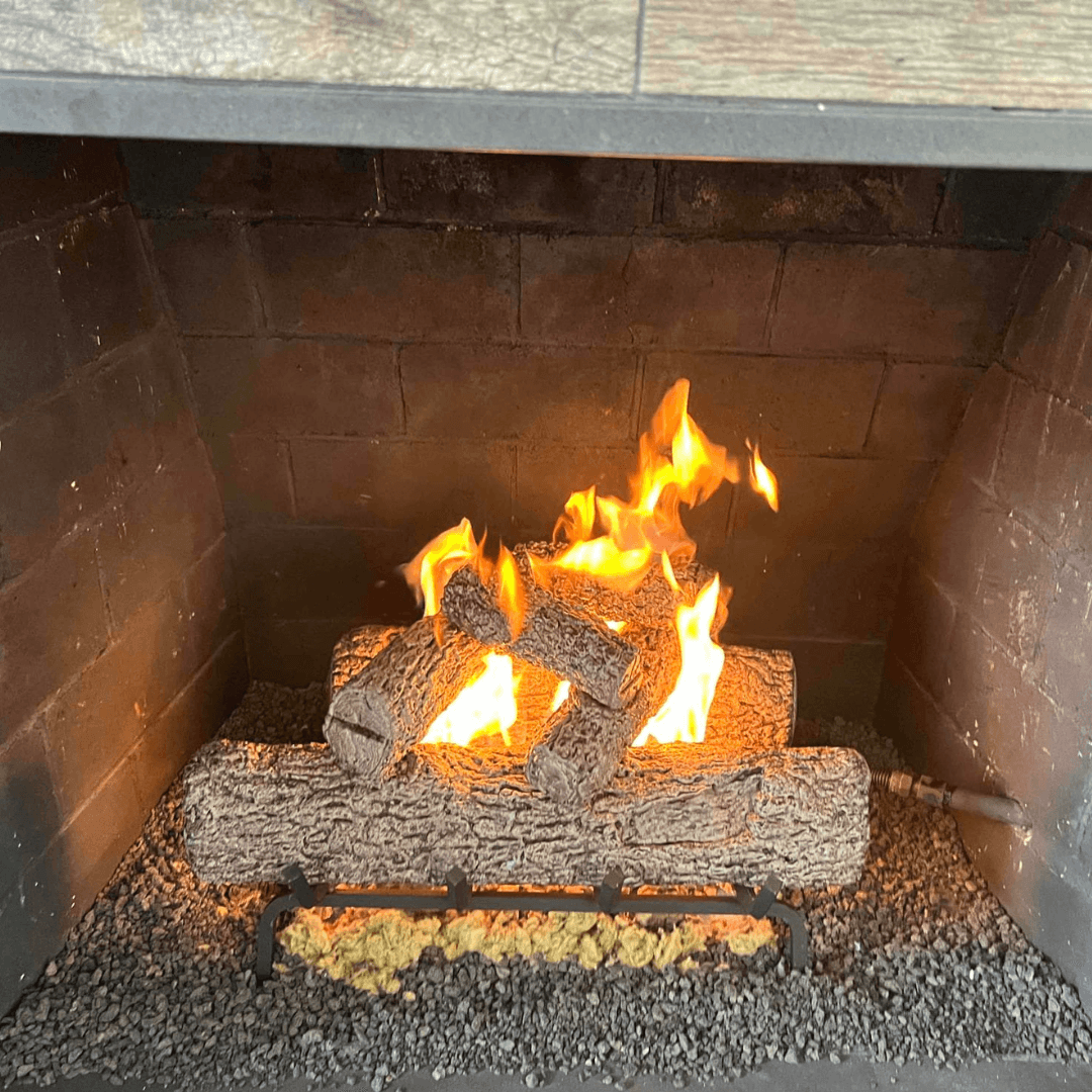High-output gas log set installed in a large brick fireplace firebox