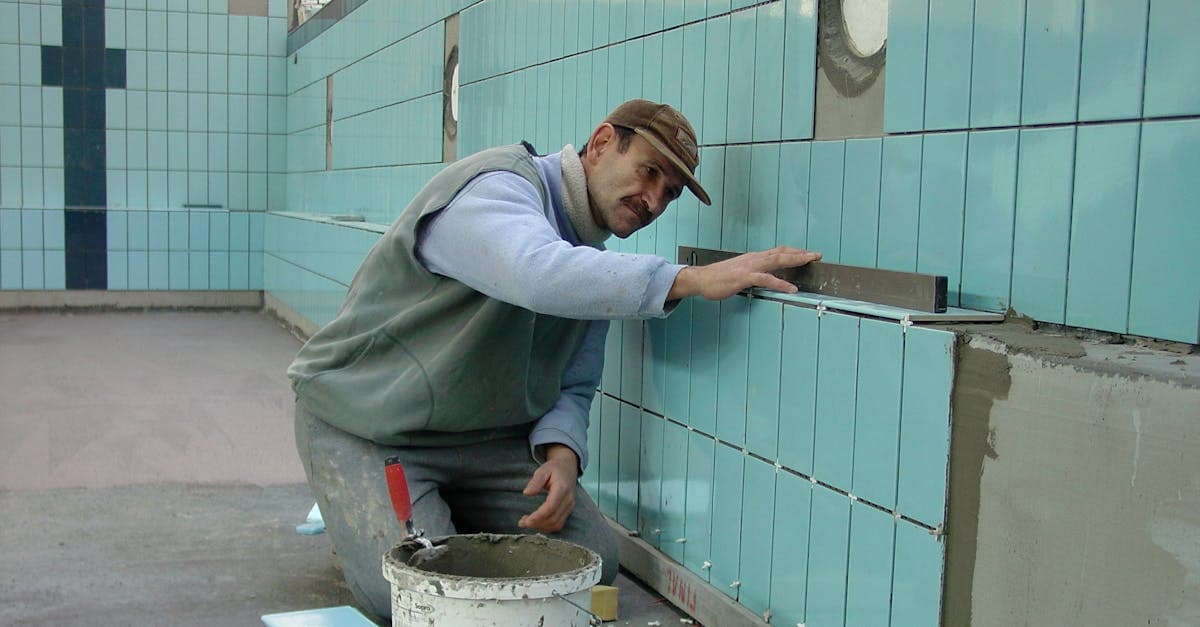 Technician setting tile on a swimming pool wall during renovation work