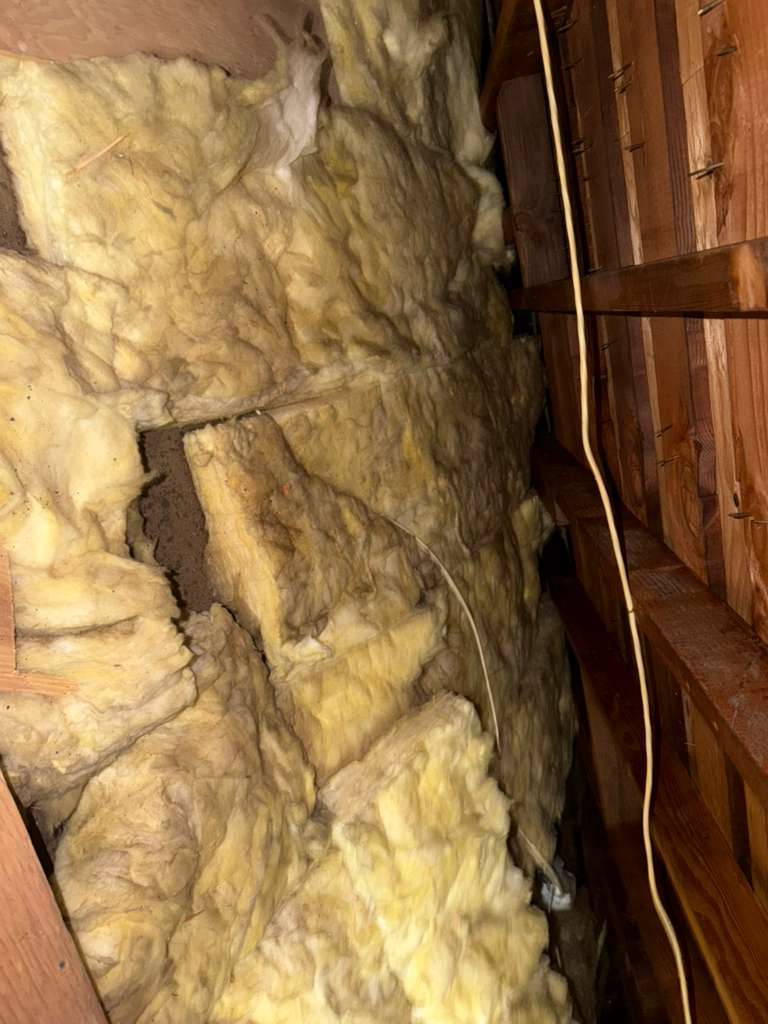 Attic space with old degraded insulation before removal
