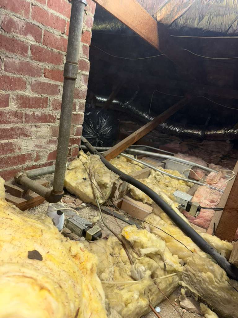 Close-up of old attic insulation showing settling and thin coverage