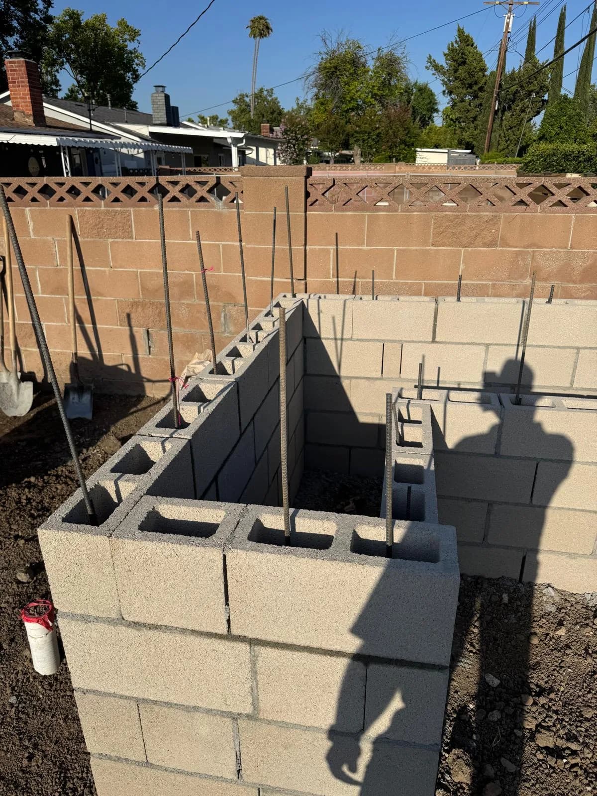 Concrete block fireplace structure under construction with vertical rebar in a backyard