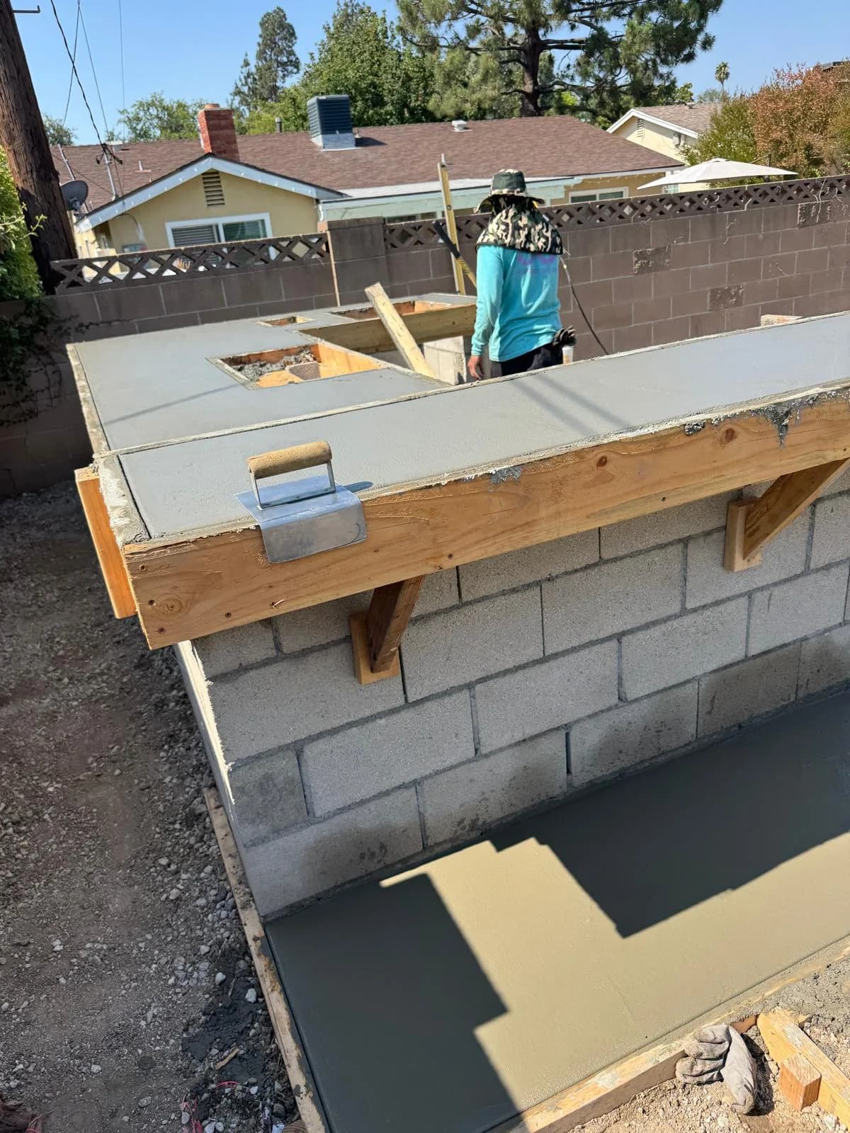 Worker smooths fresh concrete on a block structure during outdoor fireplace construction