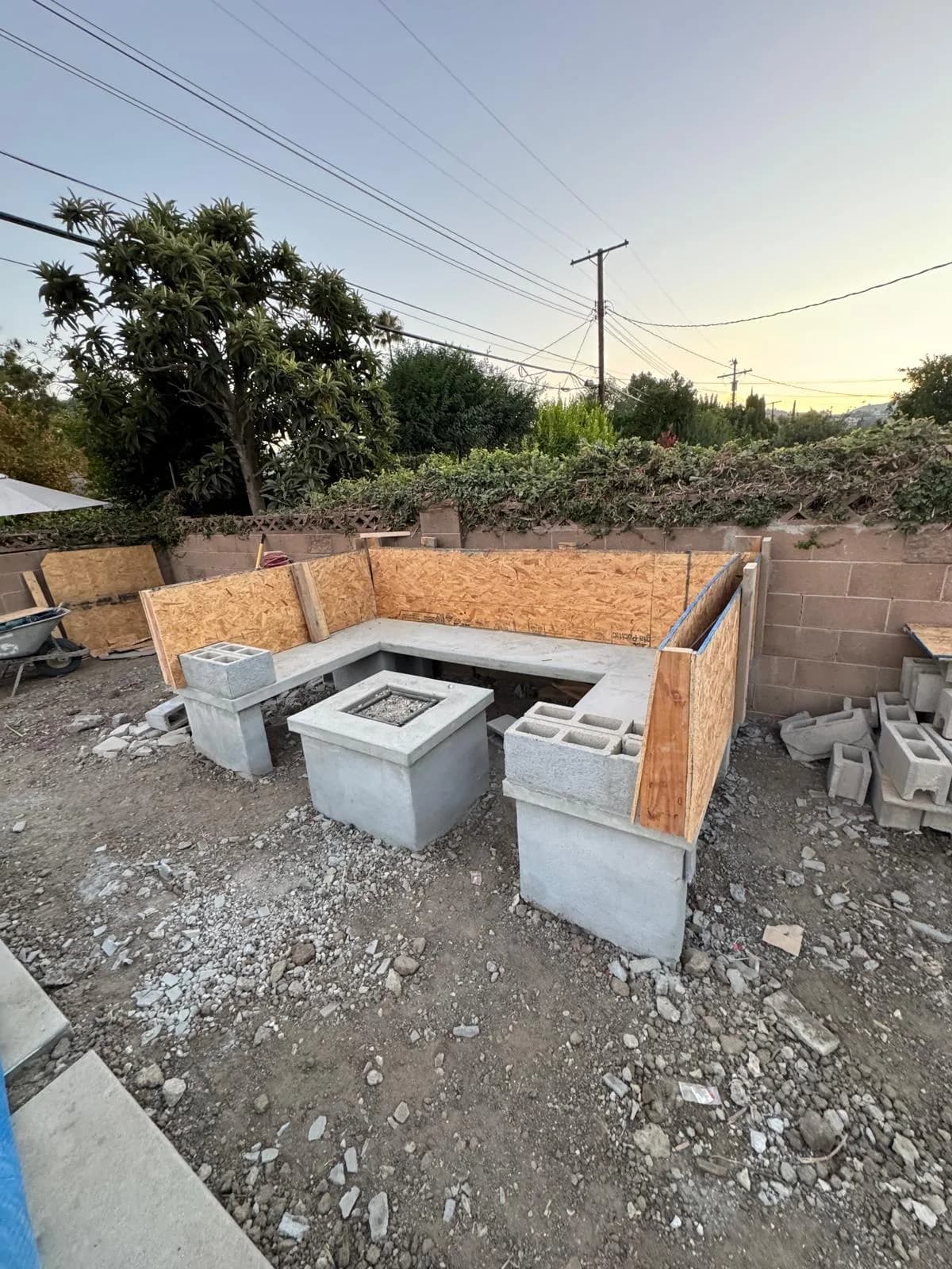 Concrete outdoor seating and fire pit under construction with plywood forms and cinder blocks in a backyard