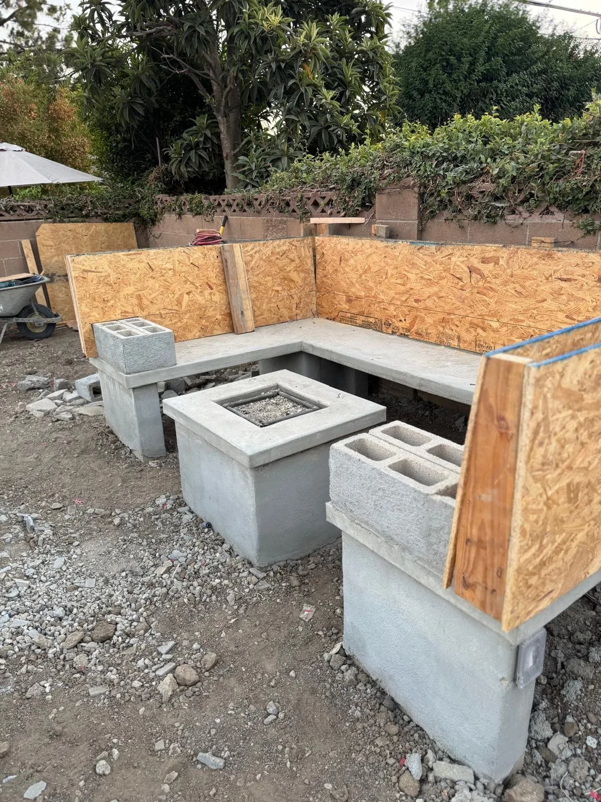 Outdoor concrete bench and fire pit under construction with plywood forms and cinder blocks