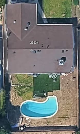 Aerial view of a backyard with a curved swimming pool behind a house