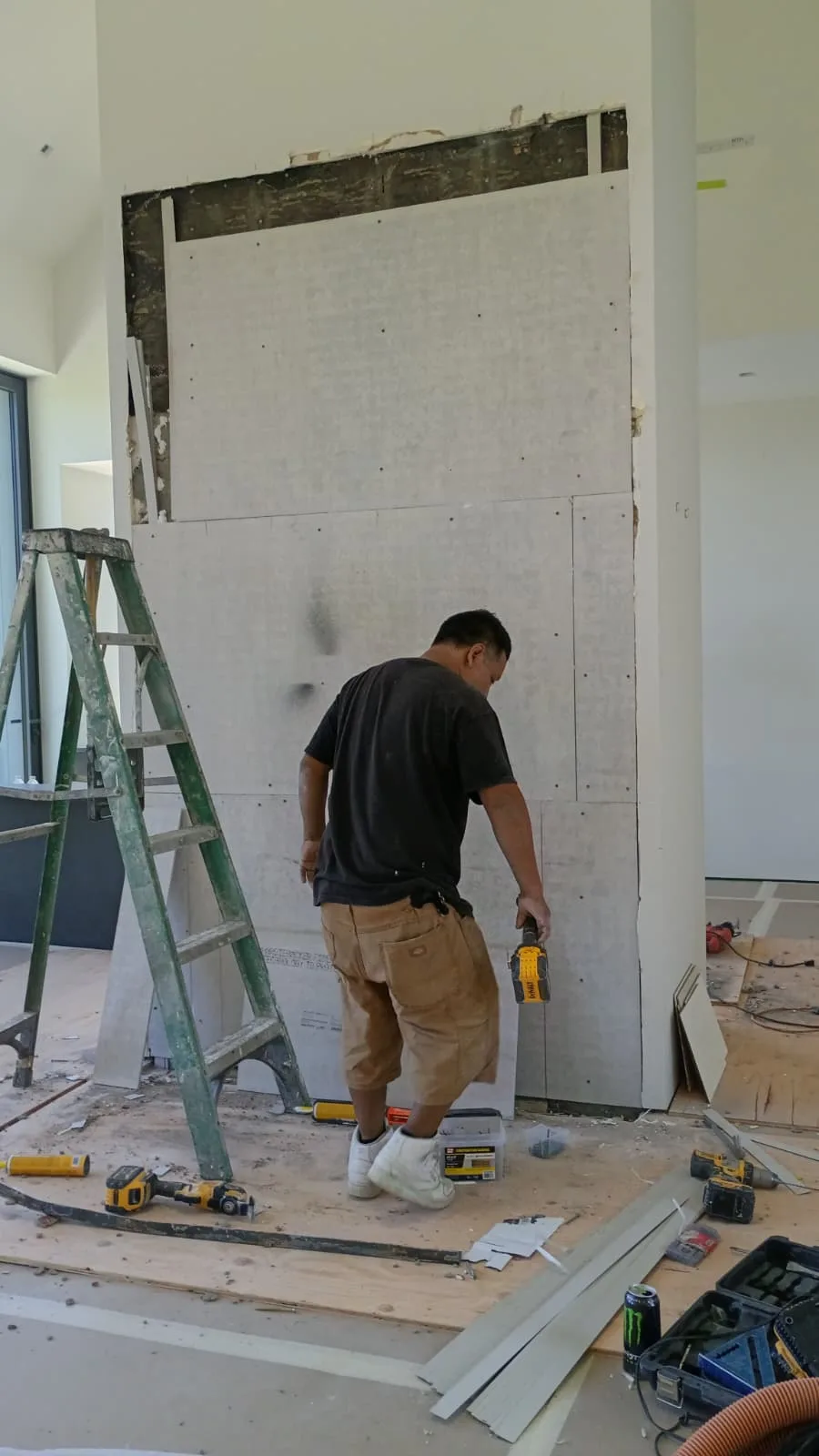 Installer cutting cement board panels beside a step ladder while reboarding the fireplace column