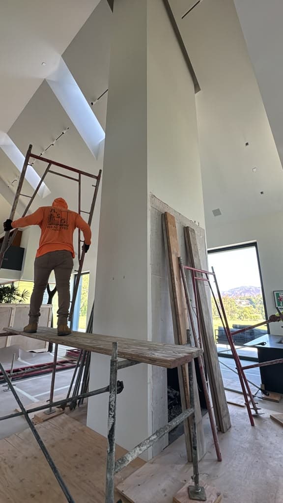 Plasterer on the scaffold platform working the full height of the fireplace column