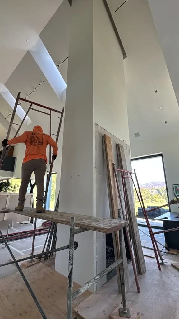Plasterer on the scaffold platform working the full height of the fireplace column