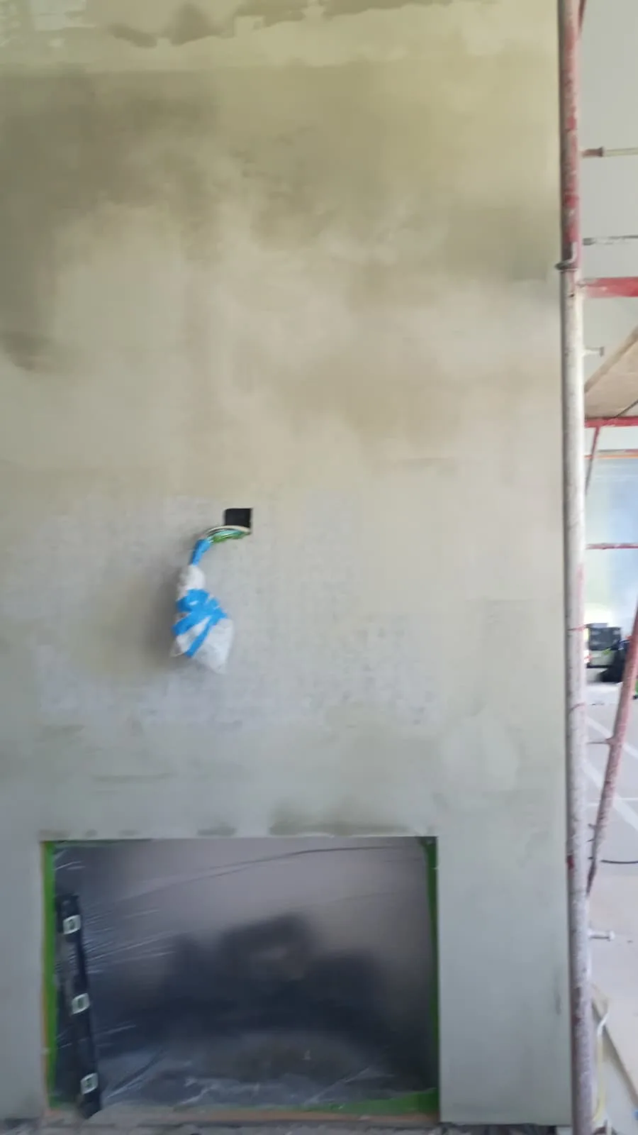 Wet Venetian plaster being troweled onto the fireplace column above the masked television recess