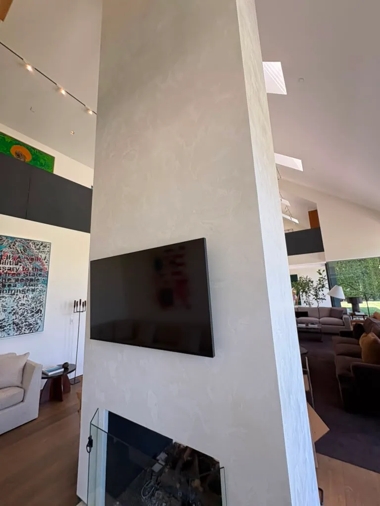 Finished fireplace column with a wall mounted television above the gas firebox and glass screen