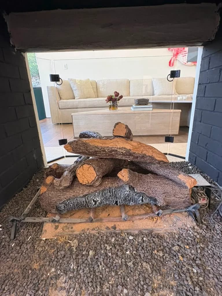 Gas log set on a lava rock bed inside the see through firebox looking out to the seating area