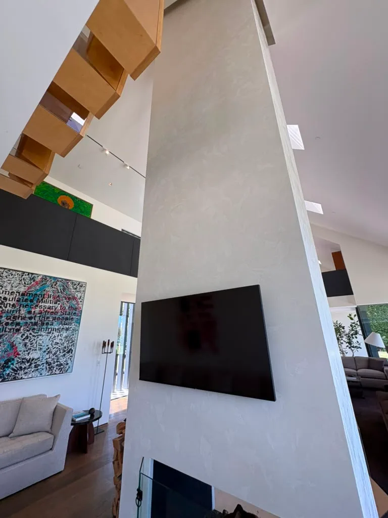 Finished plaster column with wood ceiling beams and a wall mounted television in the great room