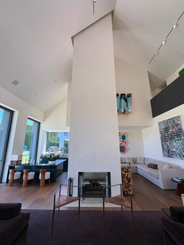 Wide view of the finished fireplace column with a fire screen and stacked firewood beside it