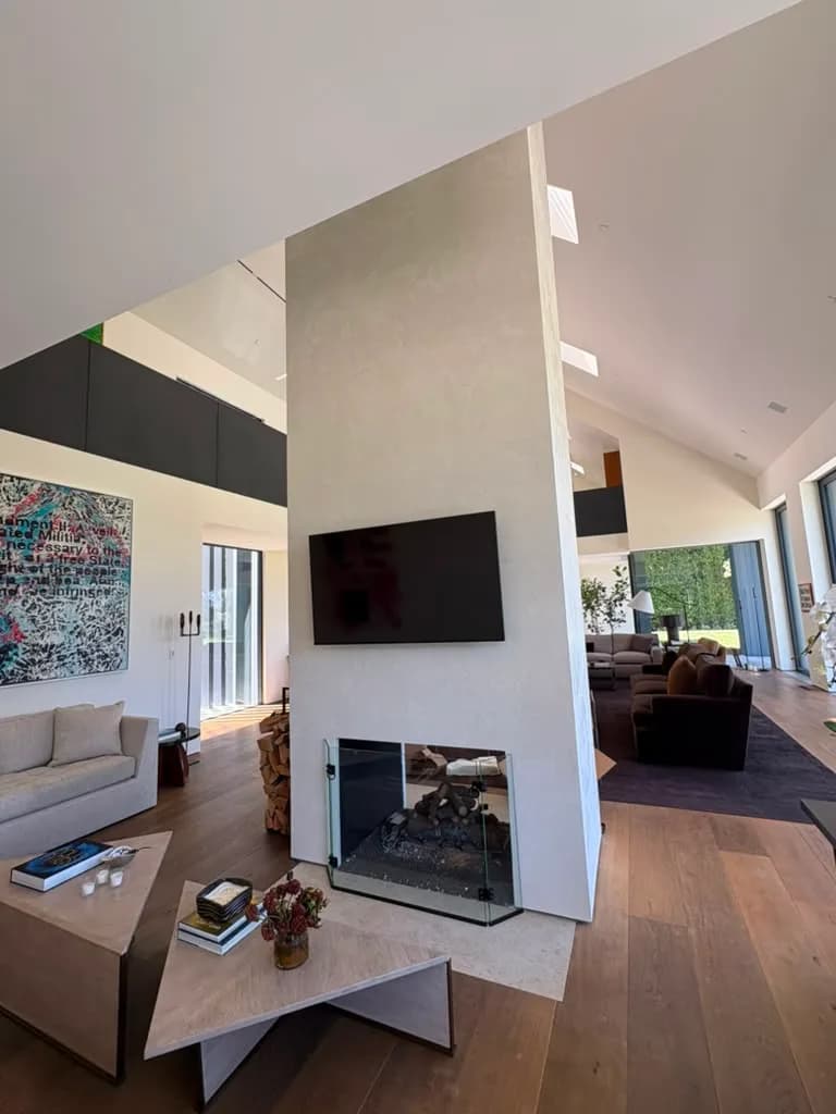 Great room with the finished fireplace column, television, and glass walls opening to the garden