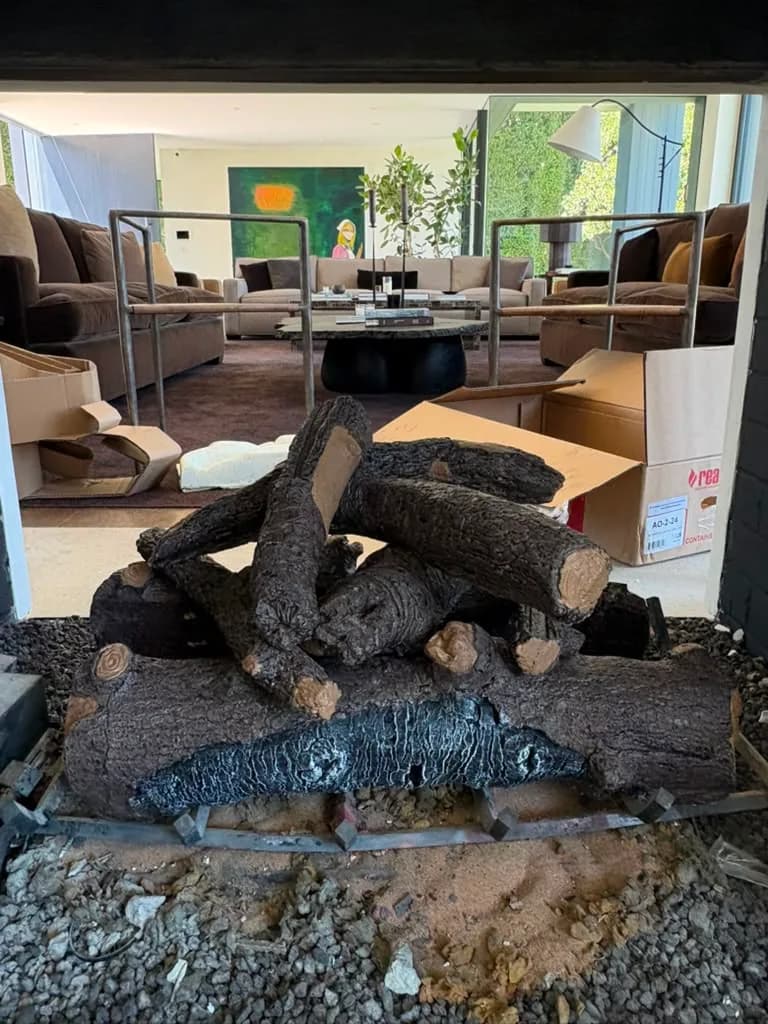 Gas logs burning low in the see through firebox with the seating area visible beyond