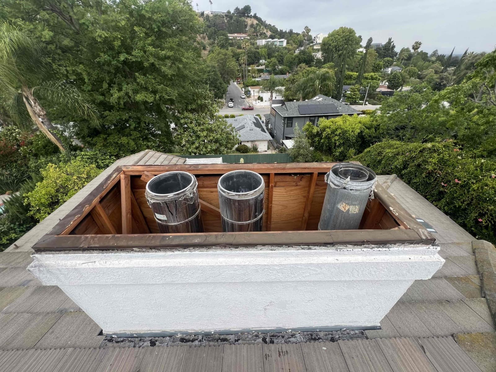 Open wood chase framing with three metal flue pipes exposed after the old cover was removed
