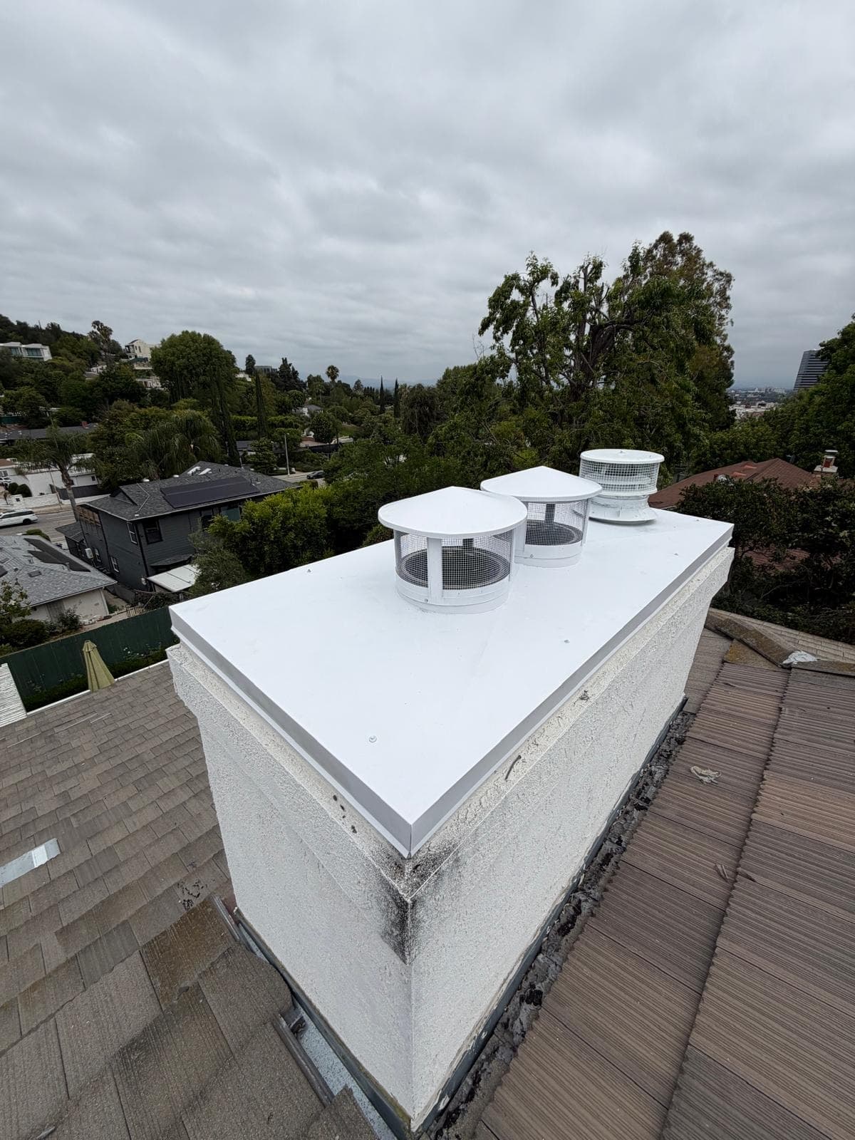 New white chase cover and matching white flue caps installed on the rooftop chimney