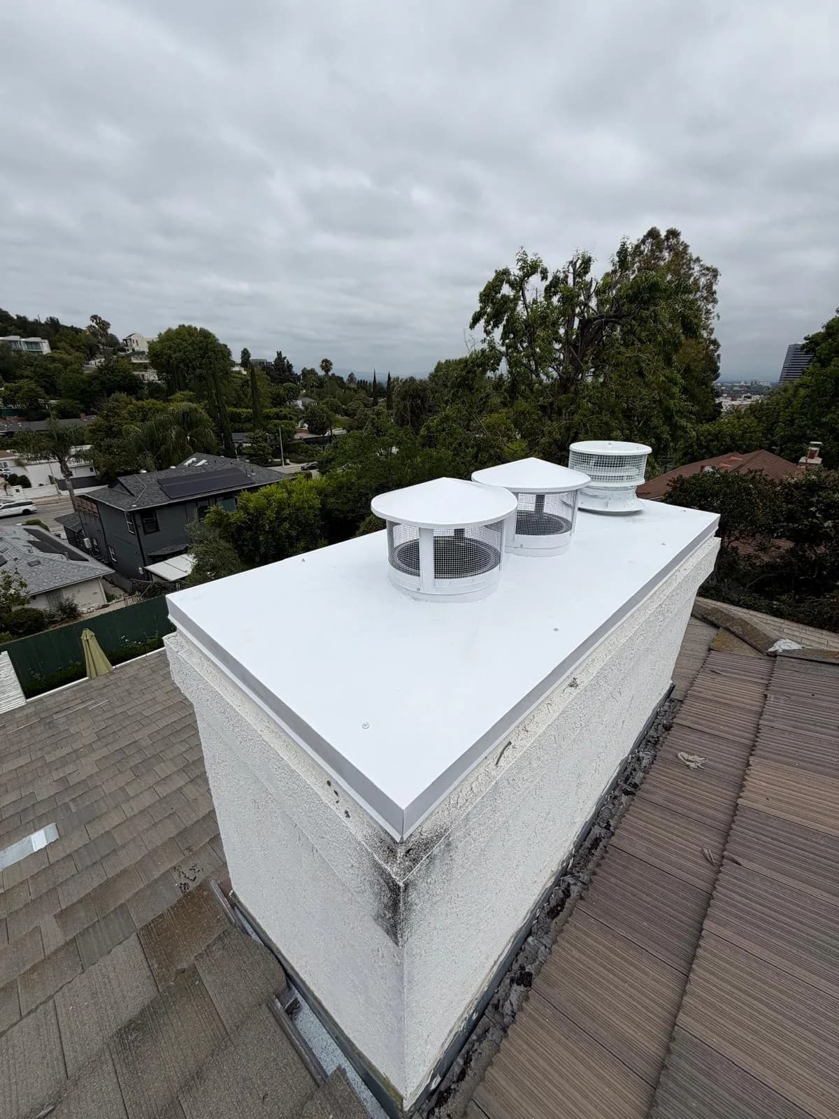New white chase cover and matching white flue caps installed on the rooftop chimney
