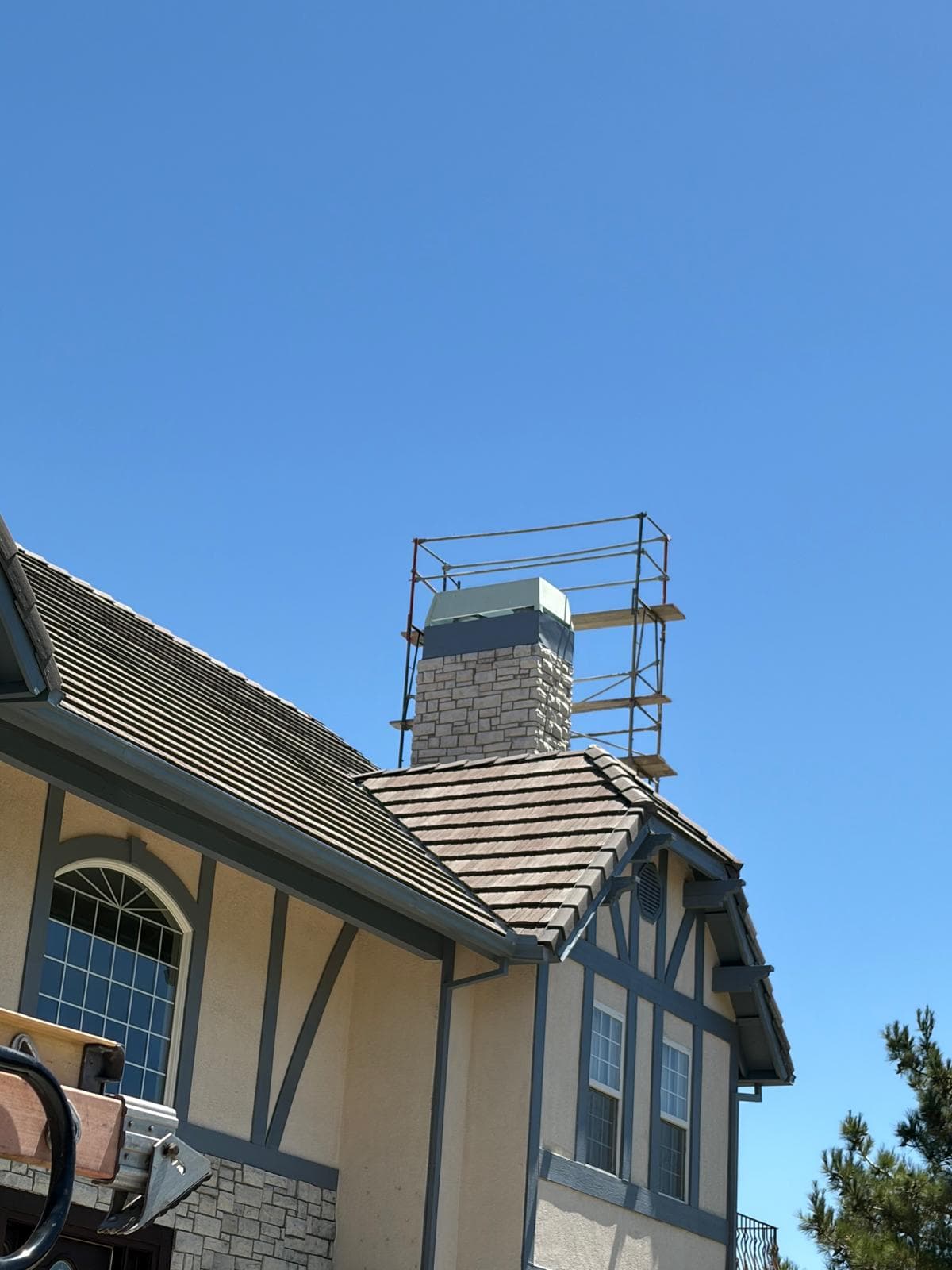 Wide exterior view of the two-story home with scaffolding visible and the chimney repair in progress