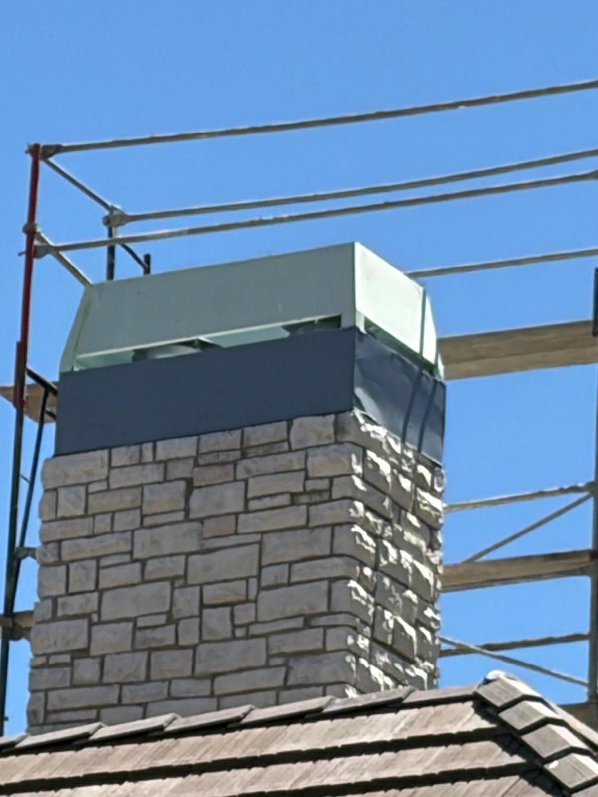 Close-up of the corrected chimney shroud and chase cover properly seated on the stone chimney top