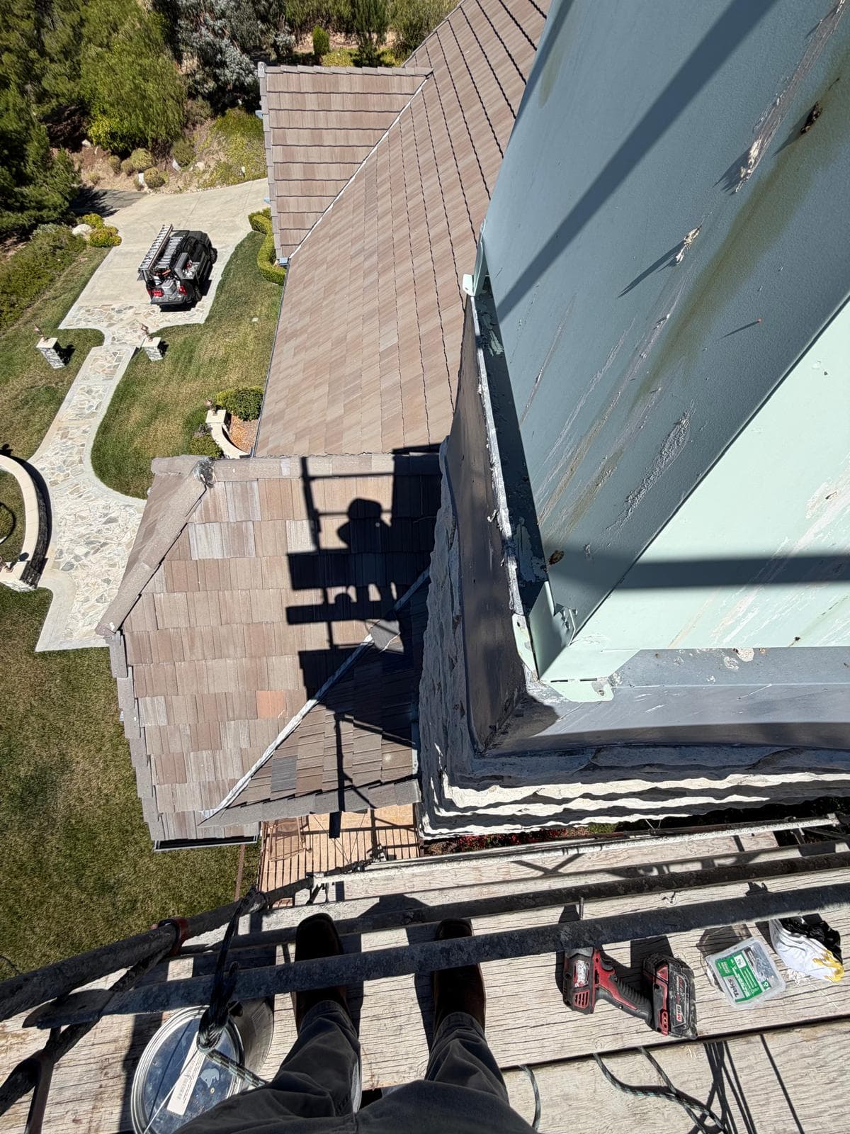 View from the top of the scaffolding platform looking down at the two-story roof and the faulty chase cover edge