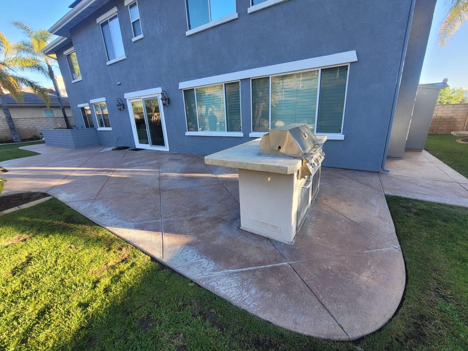 Completed stamped concrete patio with outdoor kitchen island and room addition behind