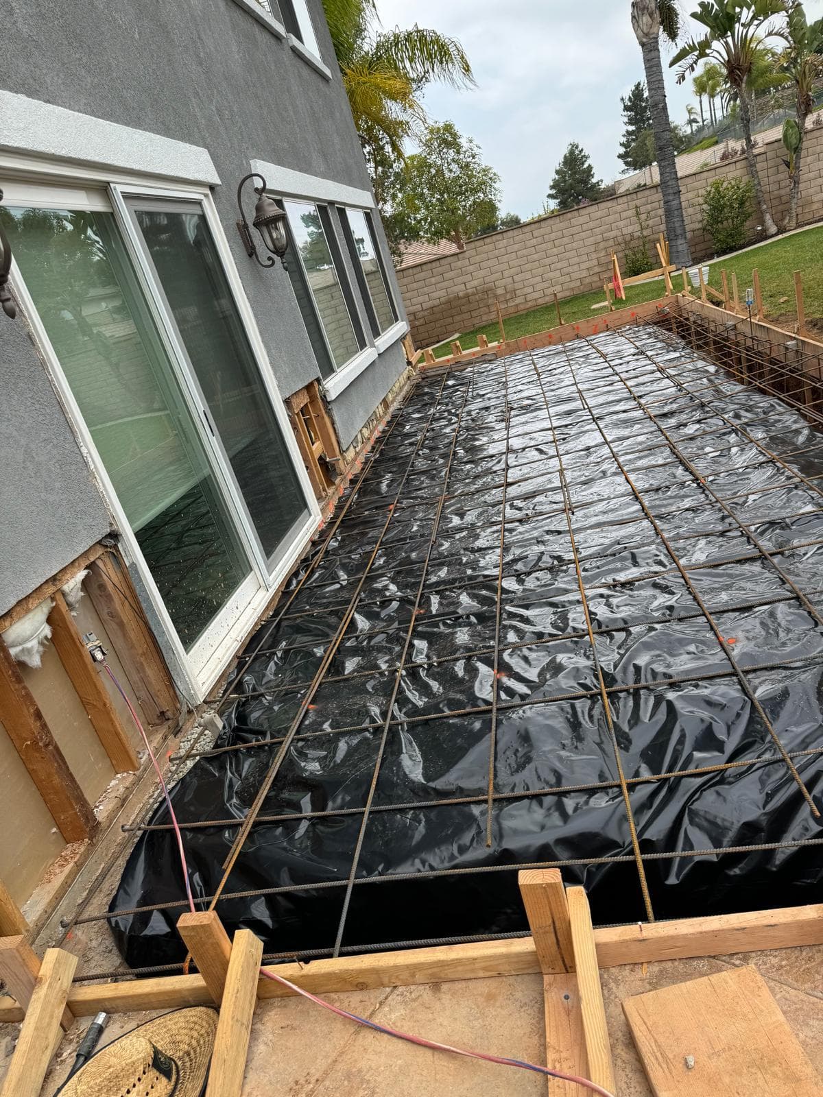 Rebar grid and vapor barrier laid out before concrete pour for patio and room addition