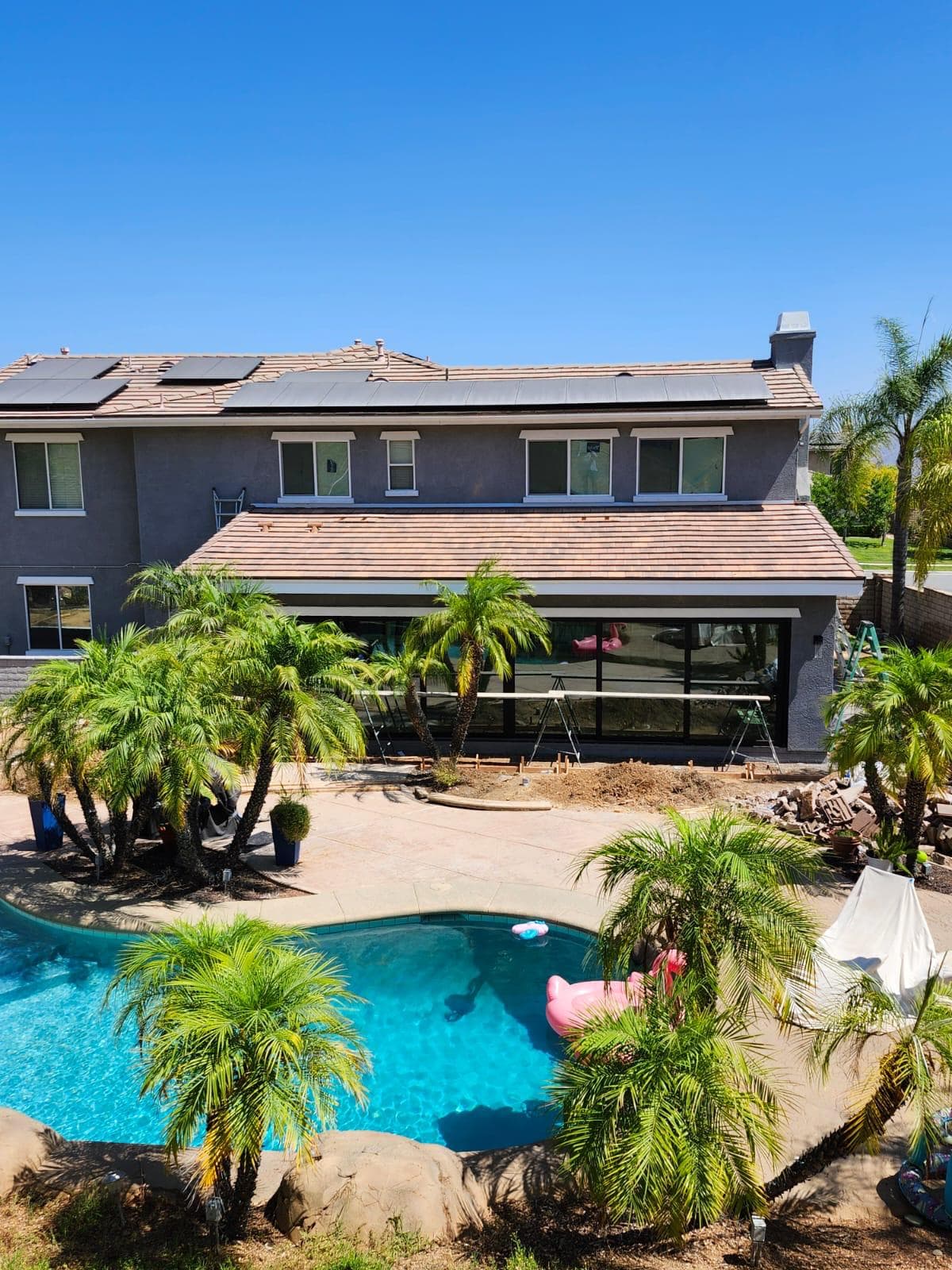 Wide aerial view of the completed home with new room addition and patio visible from above