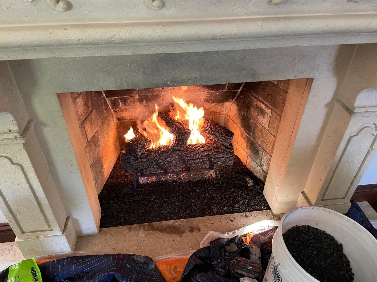Close view of a new gas log set burning over a fresh lava rock ember bed in a brick firebox