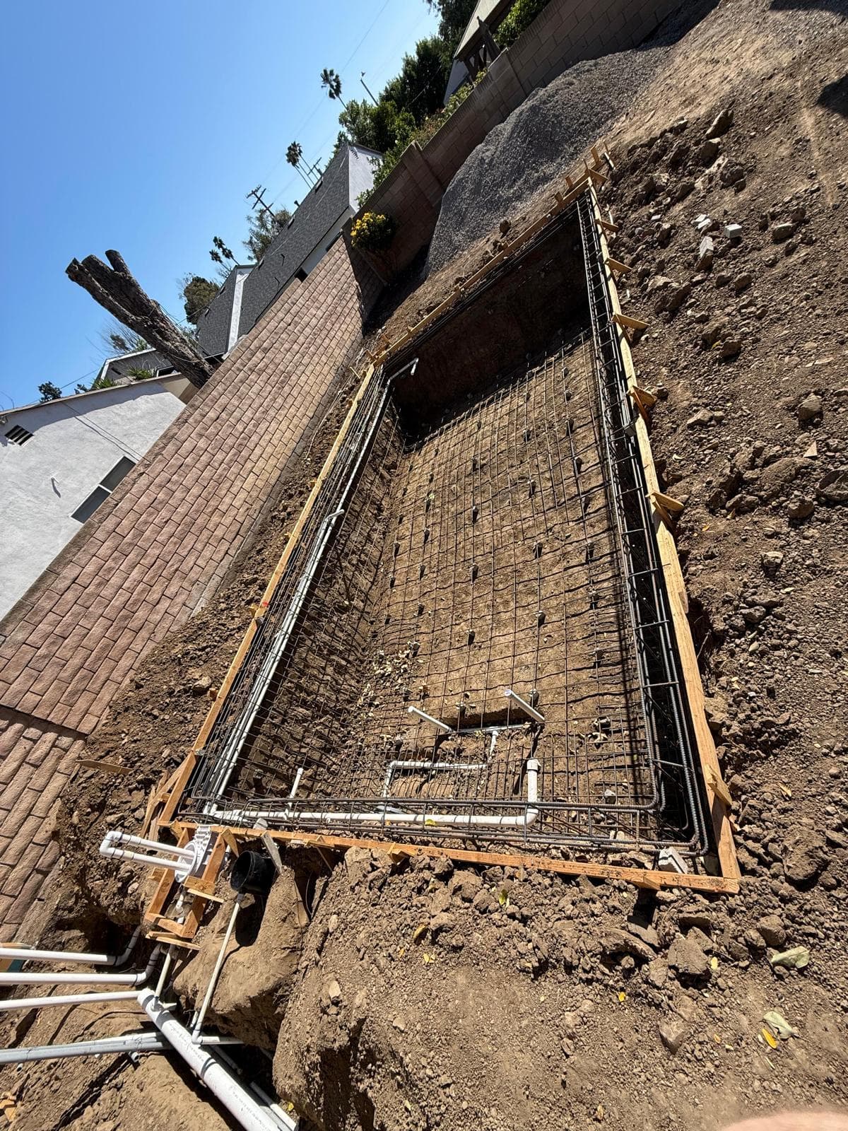 Pool excavation with full rebar and steel cage installed, plumbing rough-in visible