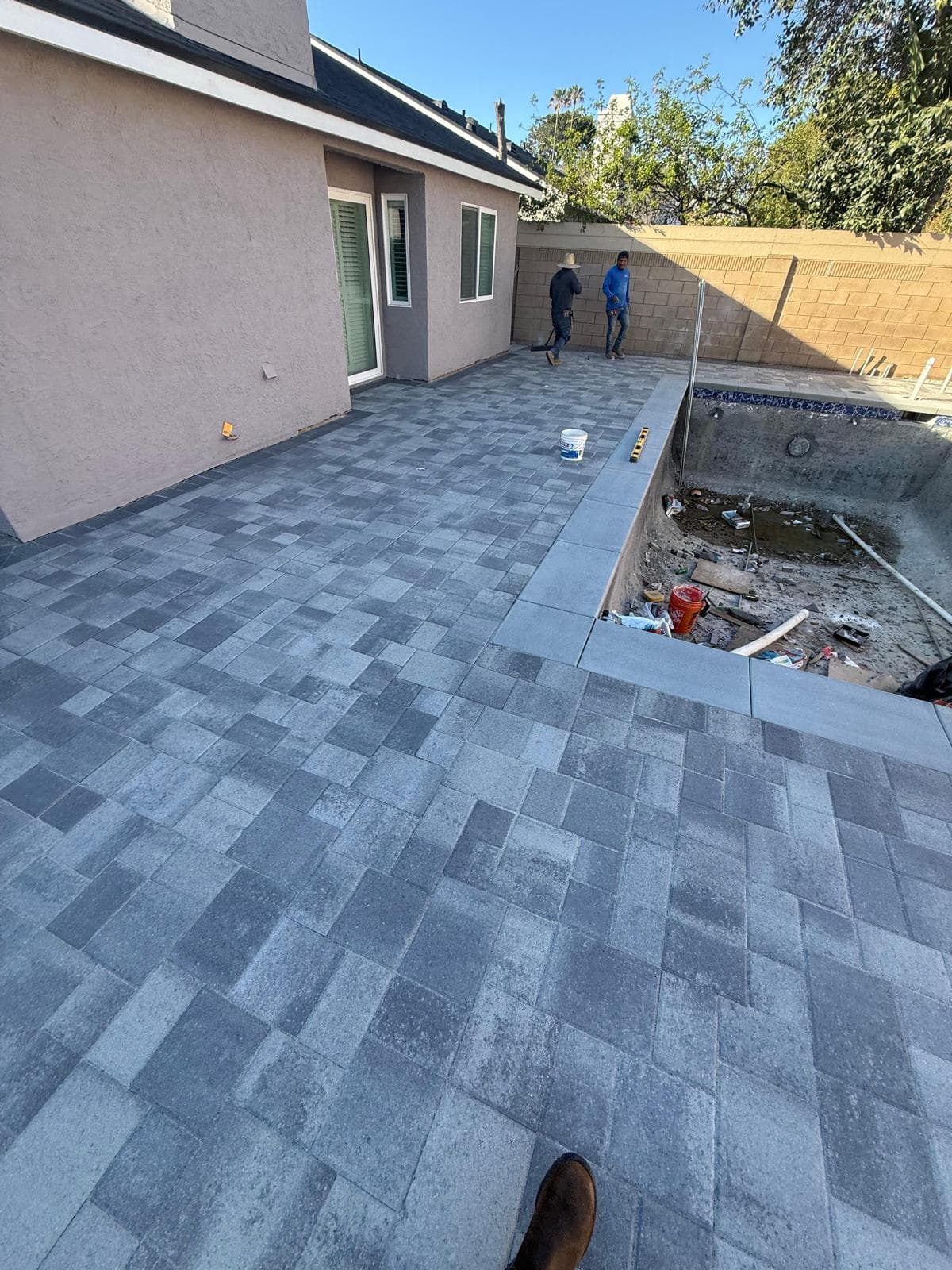 Paver deck installation around pool shell before plaster and fill