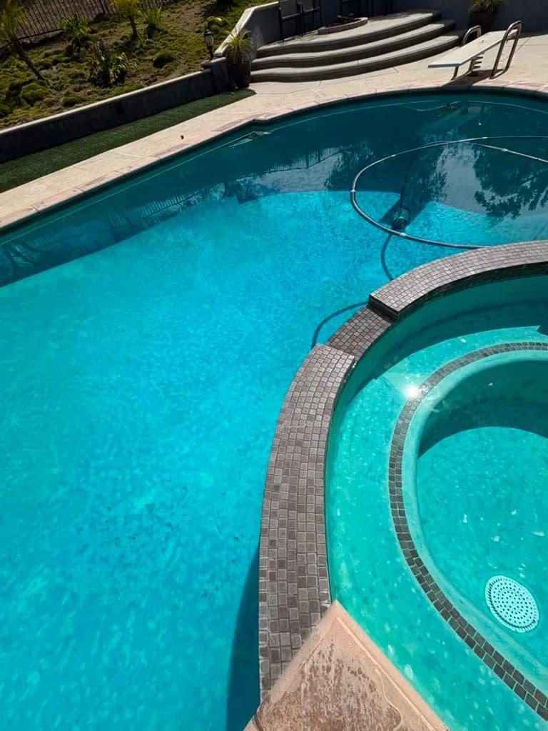 Raised spa with dark square waterline tile and stained plaster before the remodel
