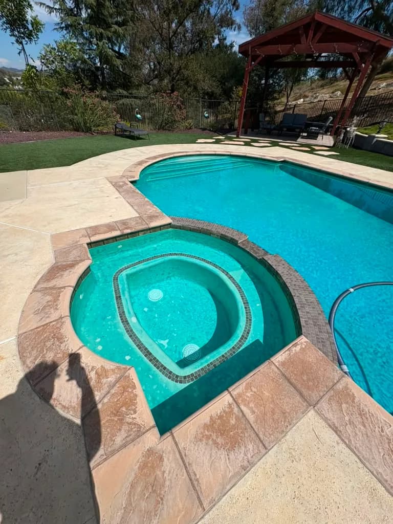 Pool and raised spa from the deck showing the worn flagstone coping and dark square tile band