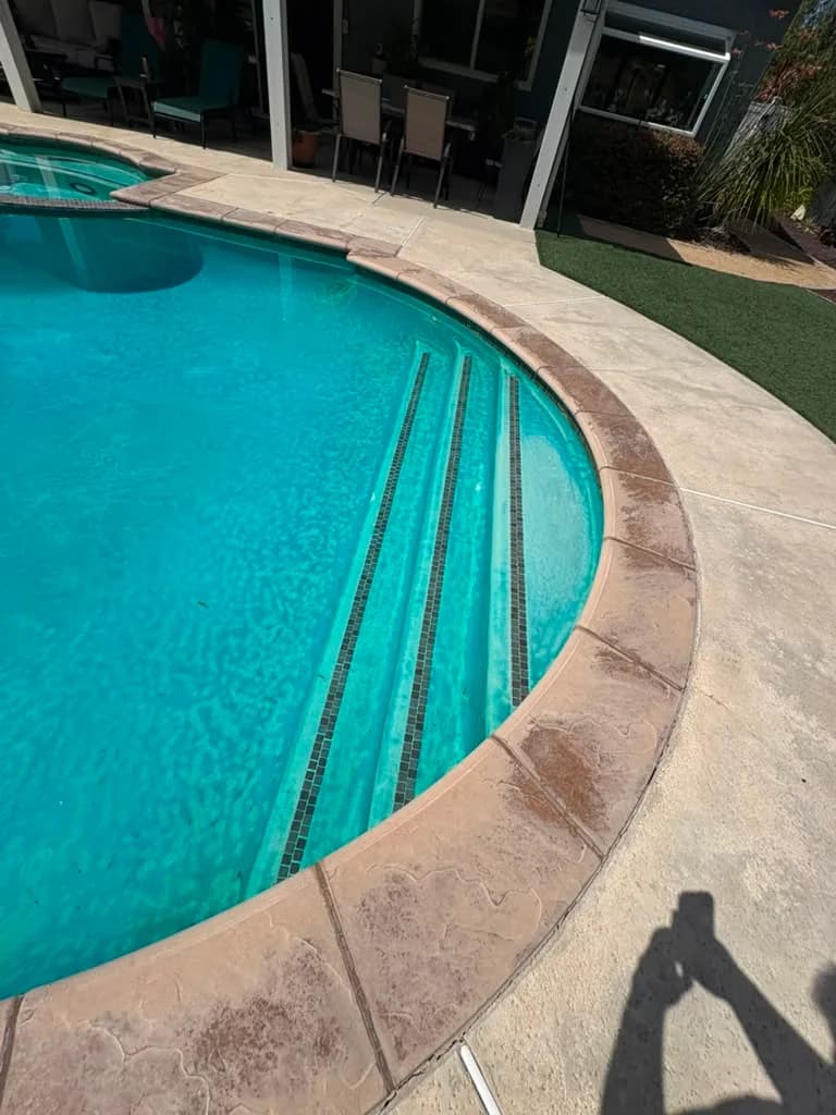 Pool steps and aged plaster before the remodel seen from the patio side of the yard