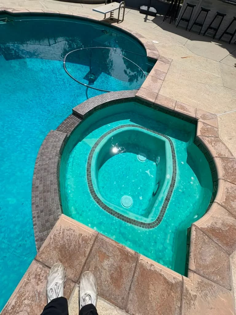 Overhead view of the spa before the remodel with dark square waterline tile and worn plaster