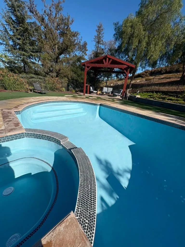 Refinished pool and spa filling with the new light blue plaster and penny round tile band