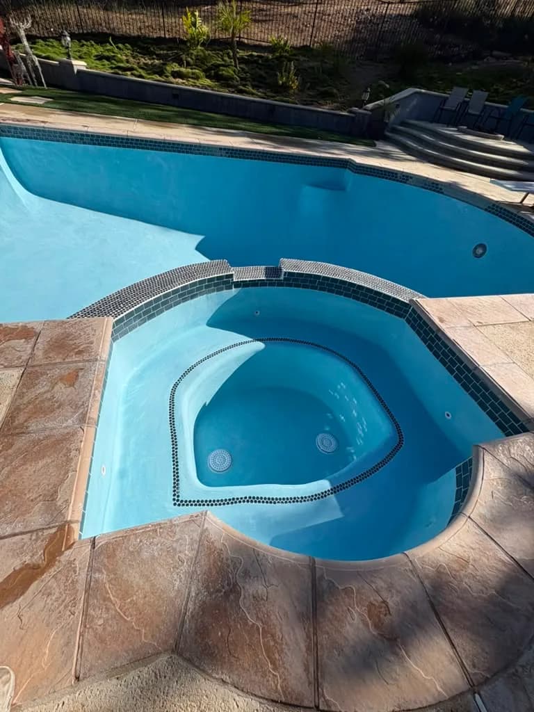 Refinished spa with new penny round waterline tile and clean light blue plaster