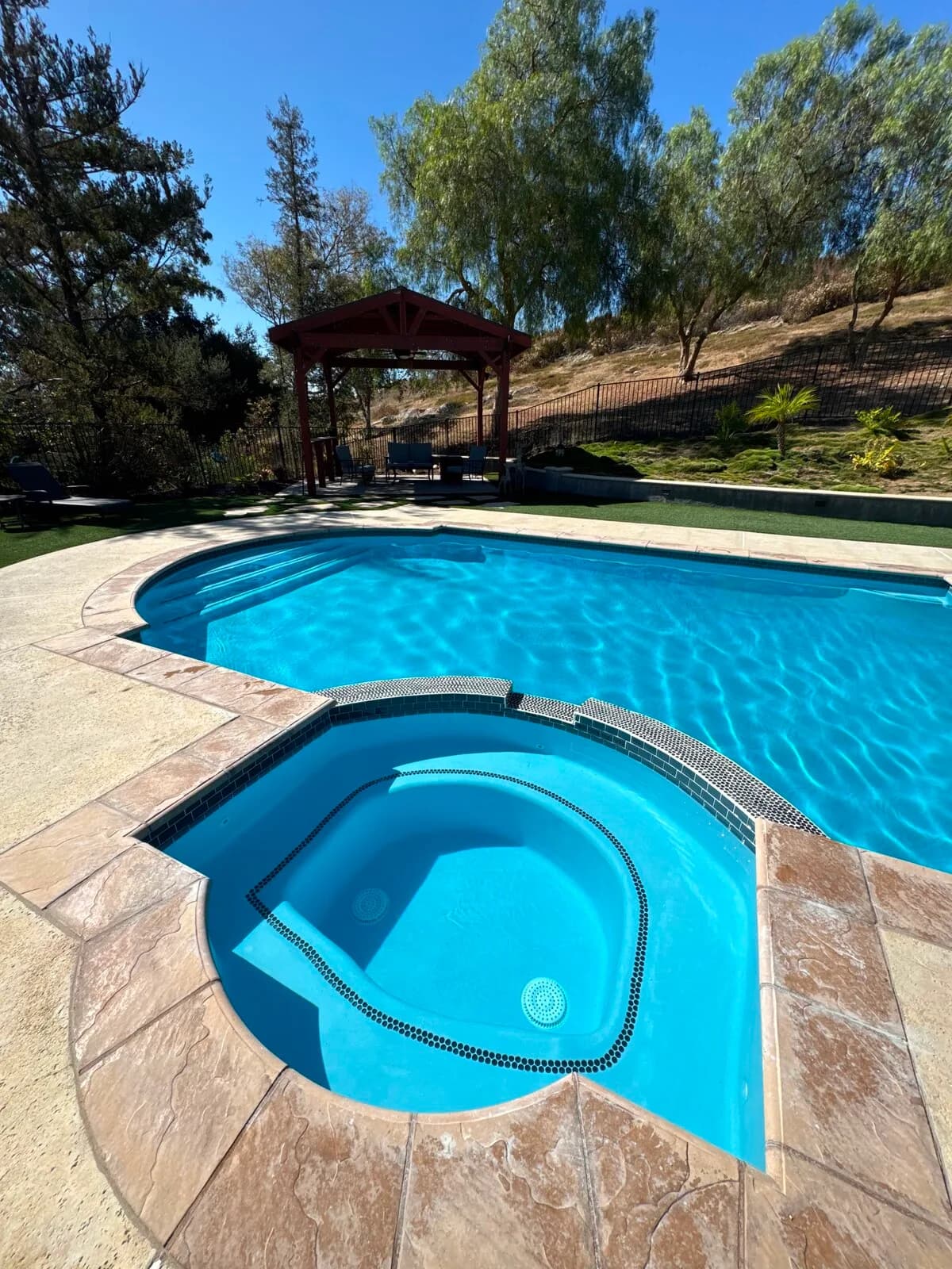 Finished pool and spa after replastering and new waterline tile seen across the deck
