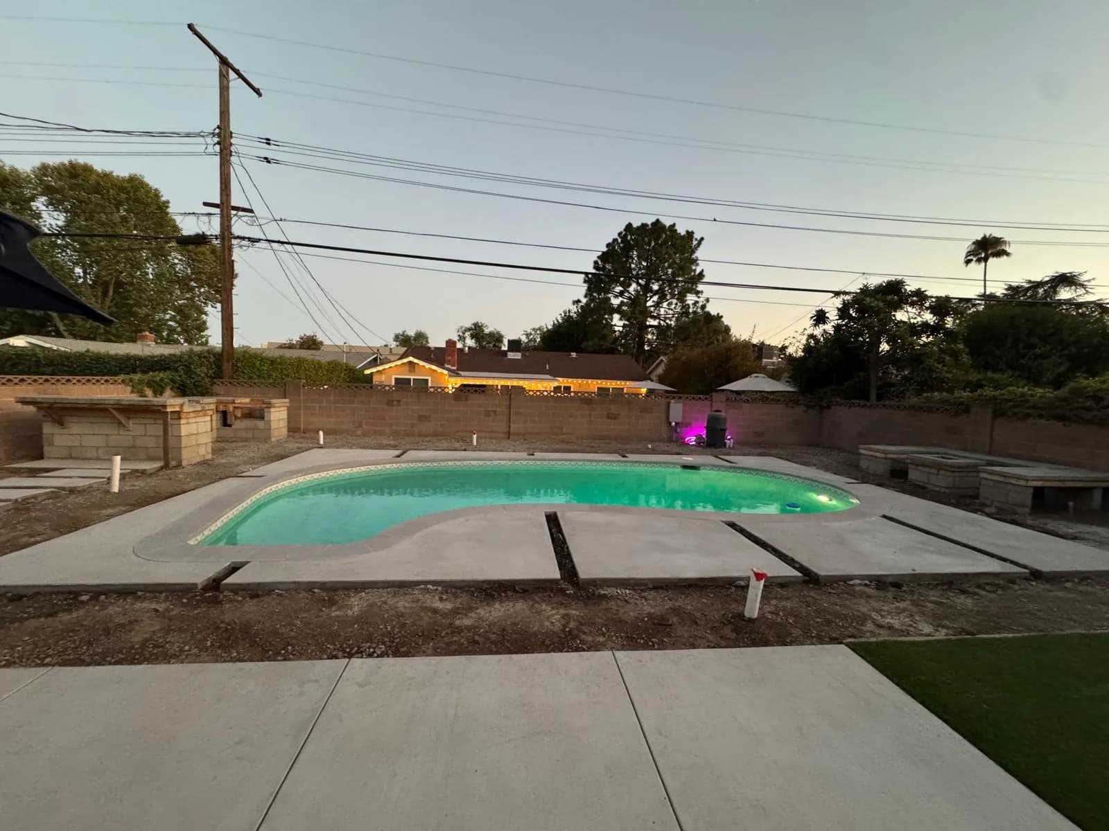 Refinished backyard pool with new deck sections and glowing water at dusk