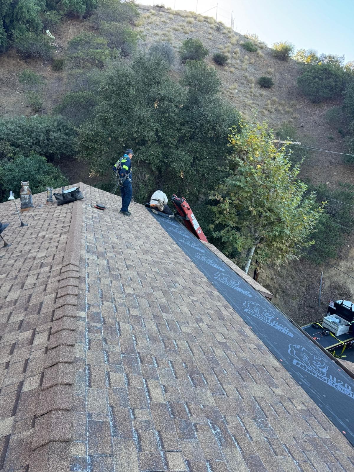 Synthetic underlayment being installed on roof deck before shingles
