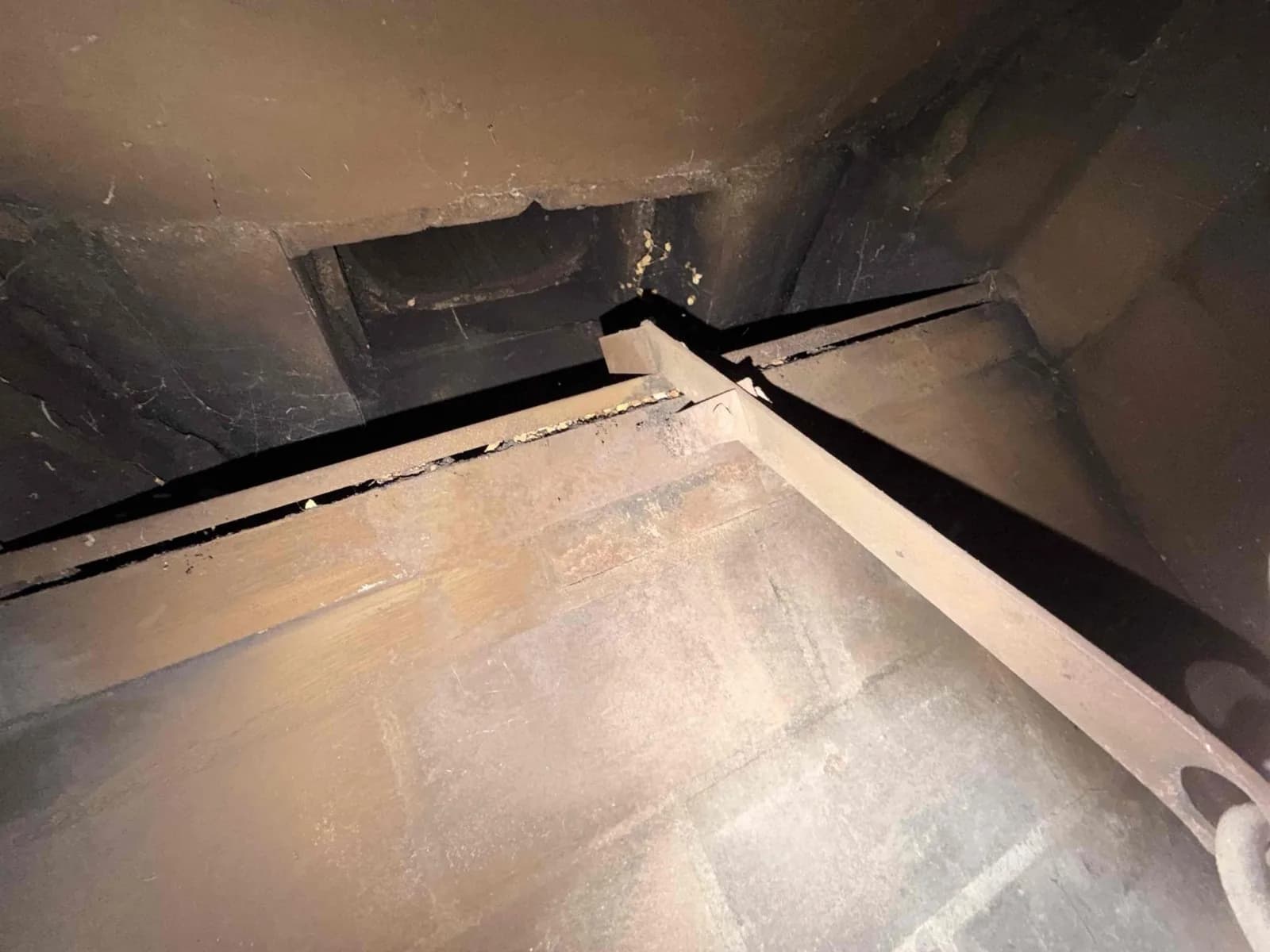 Smoke chamber before parging showing rough corbeled brick walls and creosote deposits